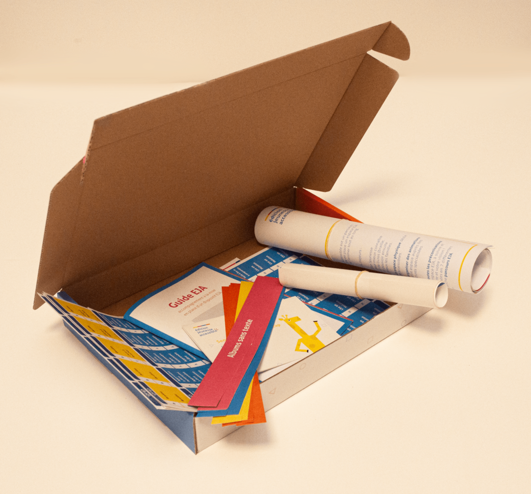 Kit EJA dans sa boite ouverte. on peut y voir des affiches roulées, des étiquettes et un Mode d'emploi.